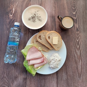 Zdjęcie przedstawia Dietę podstawową  Kawa zbożowa z mlekiem Owsianka budyniowa z bananem i jabłkiem z posypką chia Chleb mieszany pszenno-żytni Masło extra Szynka Piastowska Sałata zielona Woda mineralna Twarożek różany
